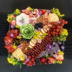 an arrangement of fruits, vegetables and meats arranged in the shape of a heart