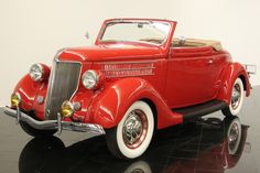 an old red car is parked on a black floor