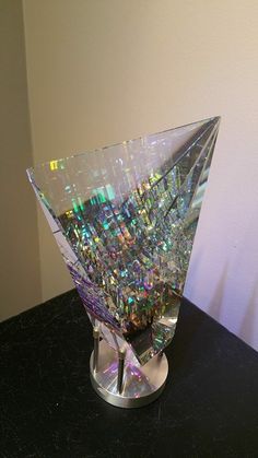 a glass vase sitting on top of a black table next to a white and green wall