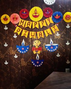 there is a sign that says happy diwali with paper decorations hanging from it