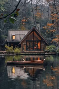 a small boat floating on top of a lake next to a house in the woods