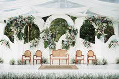 a group of people standing next to each other under a white tent with flowers on it