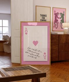 there is a pink and white framed art in the corner of this room with wood flooring