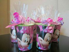 three plastic cups with minnie mouse designs and pink bows on the top, sitting on a table