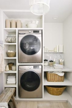 a washer and dryer in a small room with white shelves on the wall