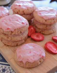 strawberry shortbread cookies with icing and strawberries on a cutting board, ready to be eaten