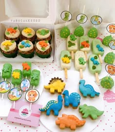 a table topped with cupcakes and decorated cookies