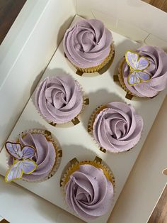 six cupcakes with purple frosting in a box