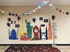 a room decorated with colorful paper cutouts and stars hanging from the ceiling above it