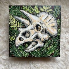 a painting of a skull in the middle of some plants and leaves on a white background