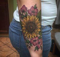 a woman's arm with a sunflower and pink flowers tattoo on the arm