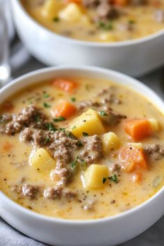 two bowls of soup with meat and potatoes on the top one bowl is filled with cheese