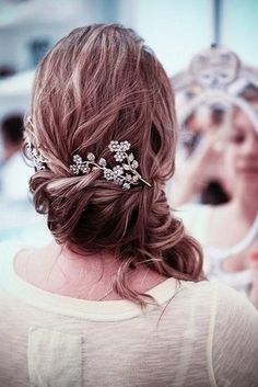 the back of a woman's head wearing a bridal hair comb with flowers on it