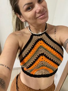 a woman wearing a crocheted crop top is taking a selfie