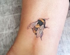 a small tattoo of a bum on the ankle, with an orange and black bee