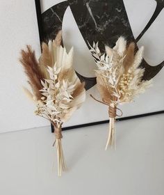 two dried flowers are placed next to each other on a table in front of a black and white art piece