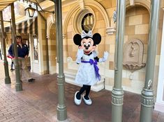 a person dressed as minnie mouse standing in front of a building with columns and pillars