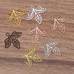 five different types of leaves on a wooden surface, one is gold and the other is silver