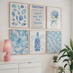 four blue and white paintings hang on the wall above a dresser with a lamp next to it