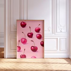 an art piece with red cherries on it in front of a white wall and wooden floor