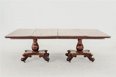 two wooden dining tables with marble top and carved wood legs, one on castors