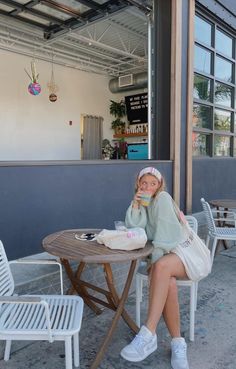 a woman is sitting at a table outside