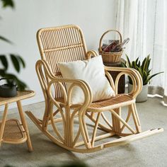 a rocking chair and table in front of a window with potted plants next to it