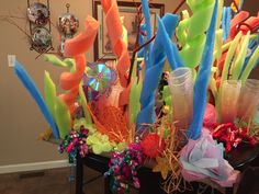 an arrangement of neon colored streamers and flowers on a table in a living room