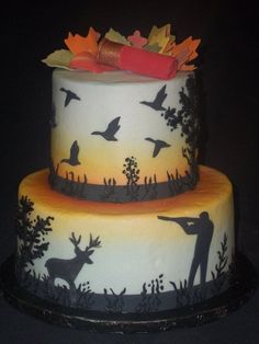 a three tiered cake decorated with deer and birds on it's sides, topped with an orange ribbon