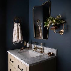 a white sink sitting under a bathroom mirror next to a wall mounted faucet