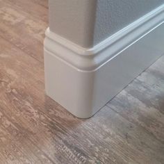 the corner of a room with wood flooring and white trim on it's walls