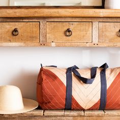 a brown bag sitting on top of a wooden bench next to a hat and vase