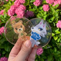 someone is holding a clear ornament with an image of a fox and a bear on it