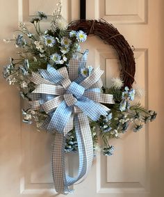 a wreath with blue and white flowers hanging on a door