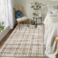 a bed room with a neatly made bed next to a chair and table in front of a window