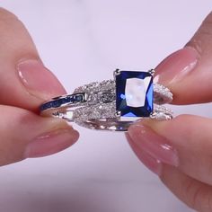 a woman's hand holding an engagement ring with blue and white stones on it