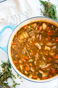 a blue pot filled with chicken and vegetable soup on top of a white tablecloth