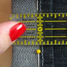 a person's finger is pointing at a piece of fabric with measuring tape on it