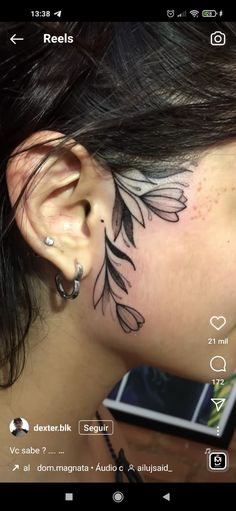 a woman's ear with an artistic tattoo on it