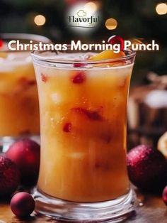 two glasses filled with drinks sitting on top of a wooden table next to christmas decorations