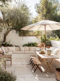 an outdoor living area with couches, tables and umbrellas