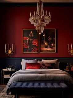 a bedroom with red walls and a chandelier hanging above the bed in front of it