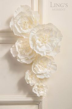 three large white flowers are hanging on the wall in front of an ornate door frame