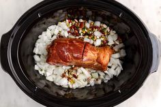 a slow cooker filled with meat, onions and other ingredients for an entree