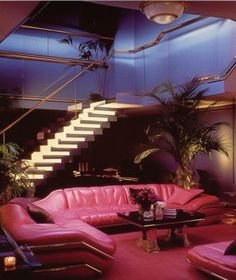 a living room filled with pink couches next to a stair case and potted plant