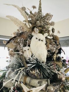 an elaborate christmas tree decorated with white and silver ornaments, feathers, branches and other decorations