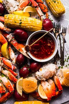 lobsters, corn on the cob and potatoes are served with red sauce