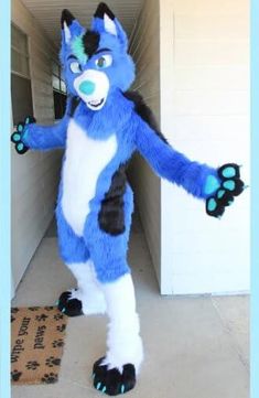 a blue and white furry animal standing in front of a door with his arms out