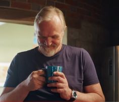 a man holding a cup looking at his cell phone