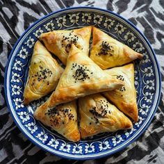 a blue and white plate topped with pastries on top of a patterned table cloth